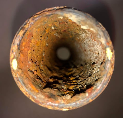 Rusty pipe interior with leak. Potential plumbing issue.